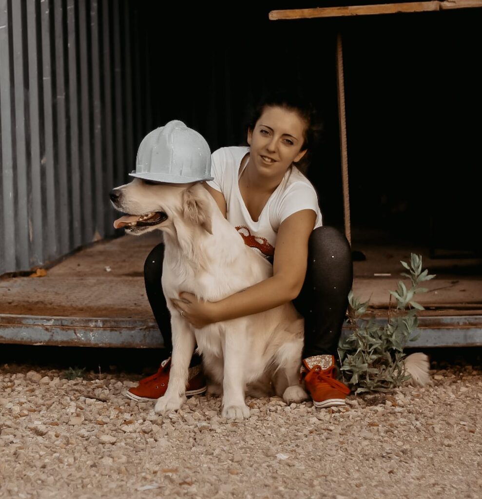 Andrea Vicedo sentada en un container con su golden retriever Frreyja sosteniendo un casco de obra